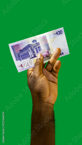 Black hand holding 20 Ghanaian cedi notes isolated on green background
 photo