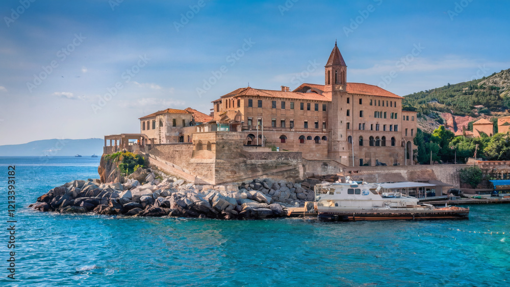 Naklejka premium A majestic, historical-looking mansion or palace perched atop a rocky outcrop overlooking a serene blue sea