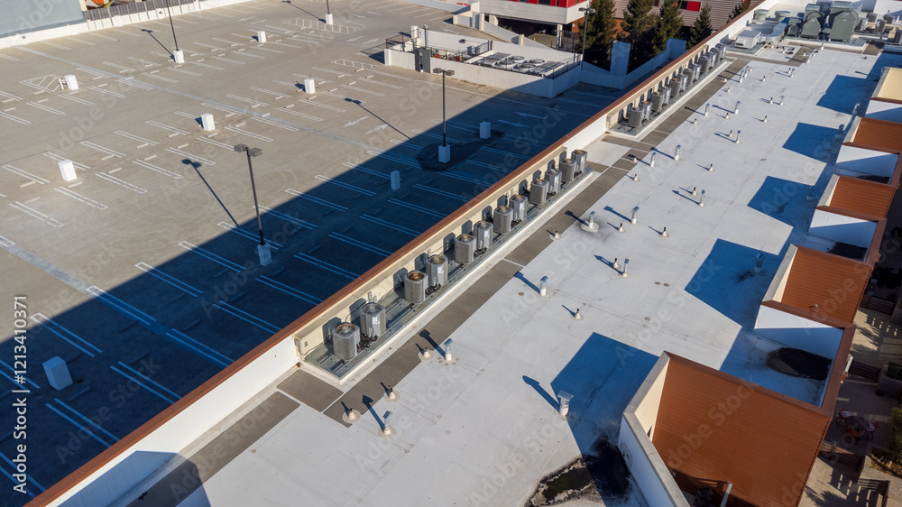 Obraz premium Aerial view of a large empty parking lot adjacent to a rooftop with HVAC units