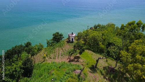 View A man stands on a viewing tower in the coastline with hills, coral cliffs, waves from the ocean in Watu Bale Beach Kebumen  Indonesia photo