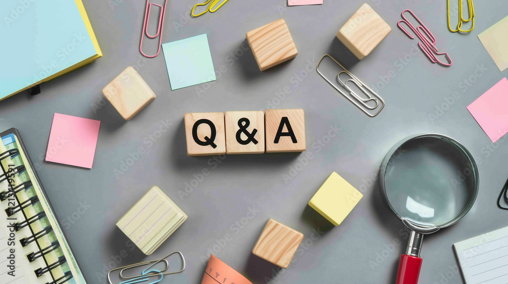 Flat lay of Q&A wooden blocks surrounded by colorful office supplies and a magnifying glass Flat lay of Q&A wooden blocks surrounded by colorful office supplies and a magnifying glass