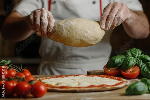 A chef skillfully preparing pizza dough with fresh ingredients like tomatoes and basil on a wooden surface. photo