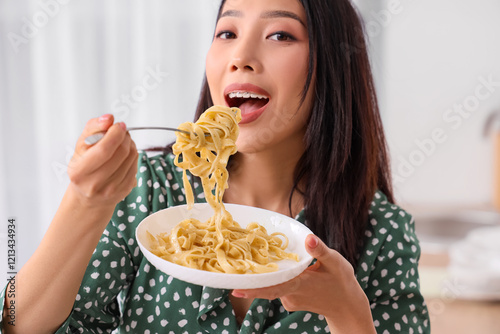 Young Asian woman eating ta...