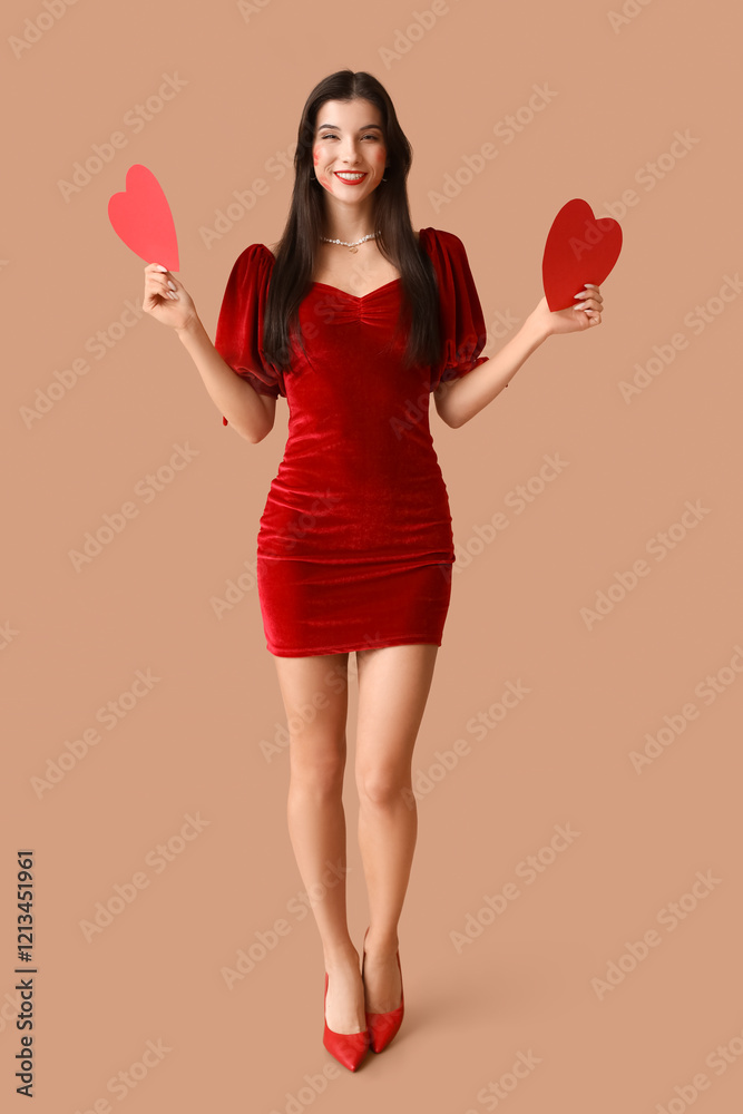 Beautiful young woman with kiss marks on her face and red paper hearts on brown background Beautiful young woman with kiss marks on her face and red paper hearts on brown background