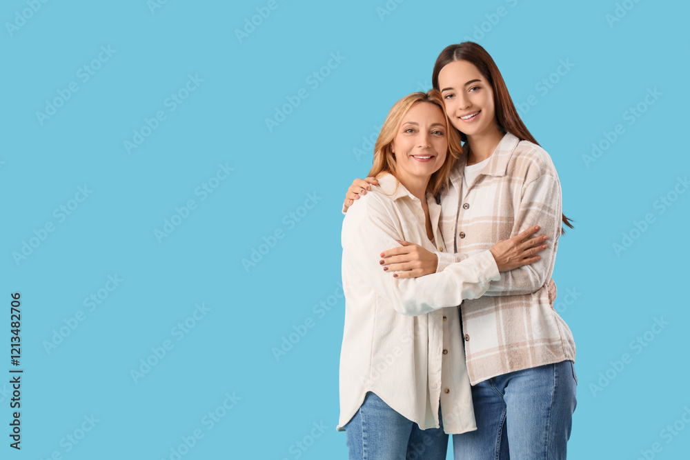 Pretty young woman hugging her mother on blue background. International Hug Day Pretty young woman hugging her mother on blue background. International Hug Day