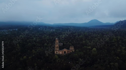 San Juan Parangaricutiro ruins surrounded by lush volcanic terrain in Michoacán, Mexico. Pan left drone aerial photo