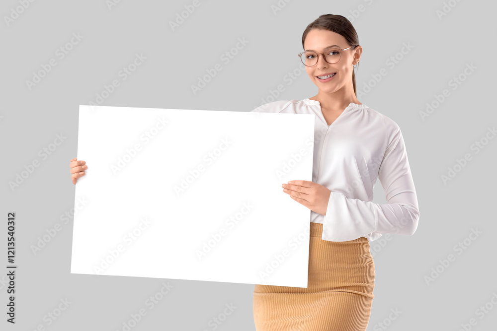 Pretty young businesswoman with blank poster on grey background Pretty young businesswoman with blank poster on grey background