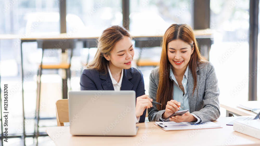 Two asian women analyzing documents while sitting on a laptop screen in office. Woman executives at work in office discussing some paperwork. Two asian women analyzing documents while sitting on a laptop screen in office. Woman executives at work in office discussing some paperwork.