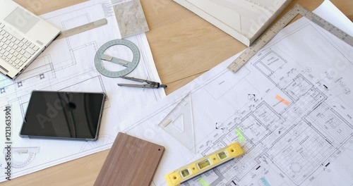 Planning construction project, architectural blueprints with tablet, compass, and level on desk