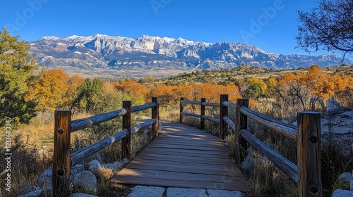 Wooden footbridge leading to majestic snowy mountain range in autumn