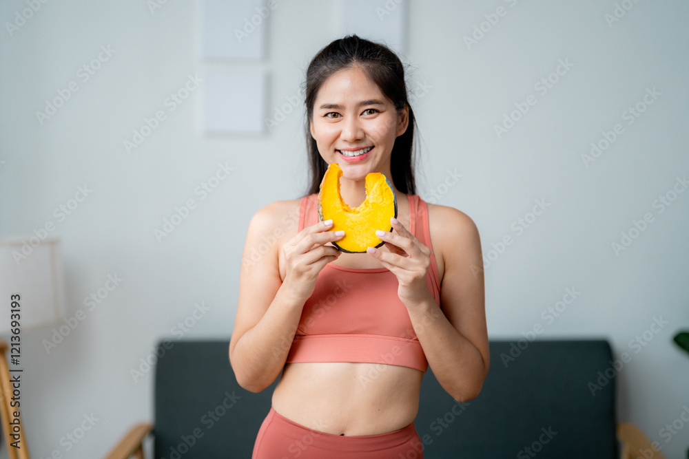 Smiling asian sportswoman showing a slice of pumpkin, promoting healthy eating habits for a fit and active lifestyle Smiling asian sportswoman showing a slice of pumpkin, promoting healthy eating habits for a fit and active lifestyle