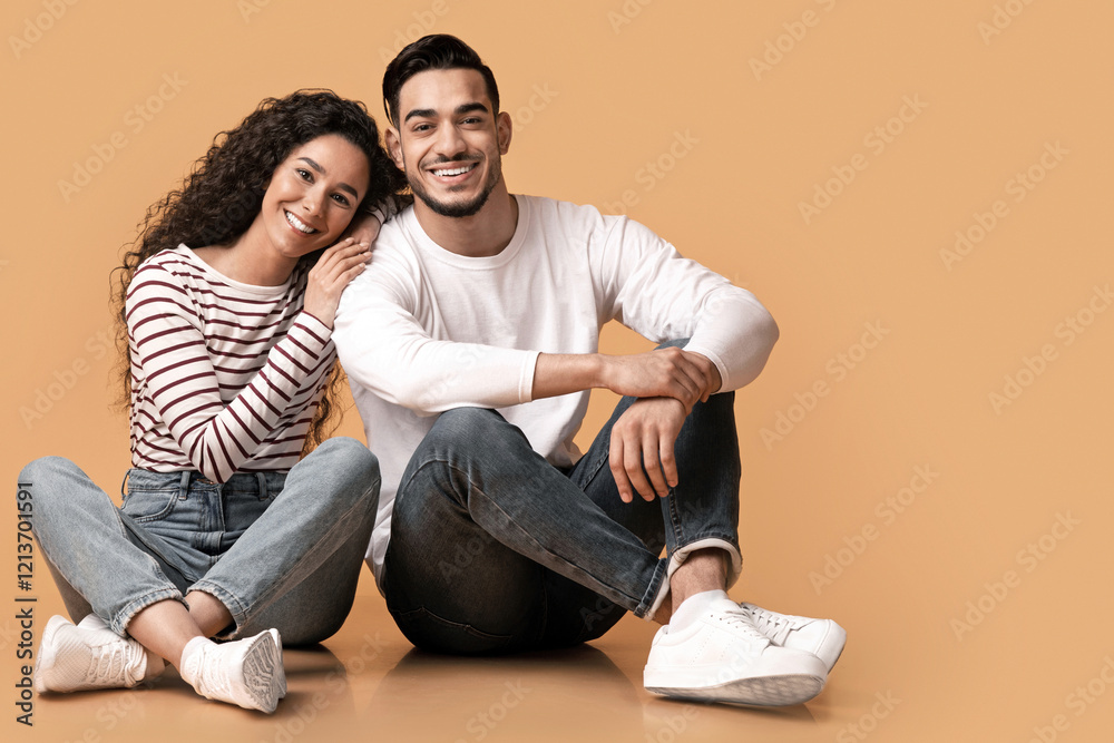 Portrait Of Happy Young Cheerful Arabic Couple Posing Over Yellow Background, Romantic Millennial Middle Eastern Spouses Sitting On Floor In Studio, Embracing And Smiling At Camera, Free Space Portrait Of Happy Young Cheerful Arabic Couple Posing Over Yellow Background, Romantic Millennial Middle Eastern Spouses Sitting On Floor In Studio, Embracing And Smiling At Camera, Free Space