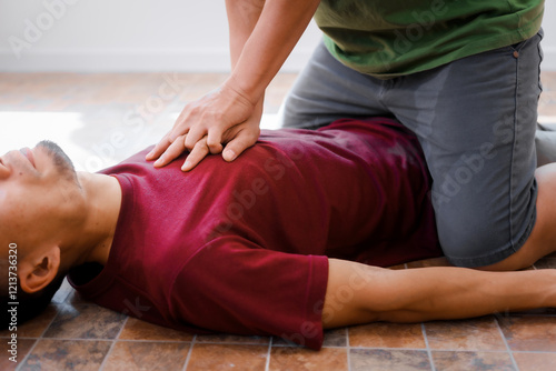 A man performing CPR on another man lying down, placing his hands on the patient’s chest to ensure safety, monitor heart rate, provide emergency services, and maintain health care and body integrity