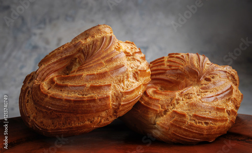 Two profiteroles lie in a clay plate. The eclair is in the shape of a ring. photo