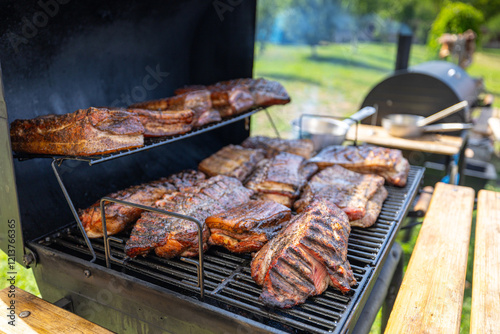 Obraz na płótnie Close-up of meat smoking on a BBQ smoker outdoors, highlighting rich flavors and barbecue culture. Grilled pork meat and beef food. Outdoor cooking. w salonie