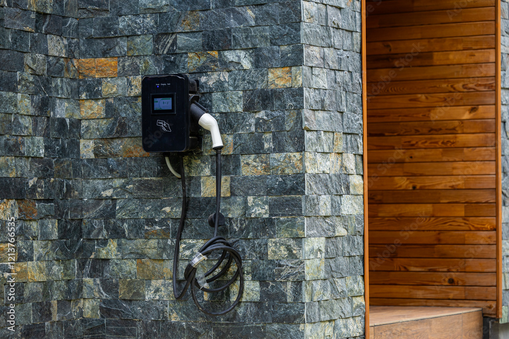 Wall-mounted electric car charging station outside a modern house, representing sustainable transportation. Electrical cars industry.