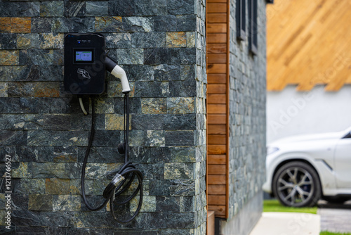 Wall-mounted electric car charging station outside a modern house, representing sustainable transportation. Electrical cars industry.
