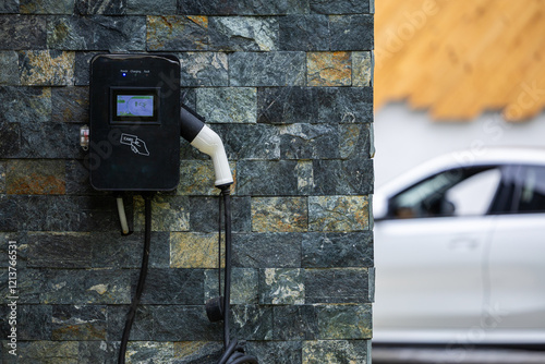 Wall-mounted electric car charging station outside a modern house, representing sustainable transportation. Electrical cars industry.