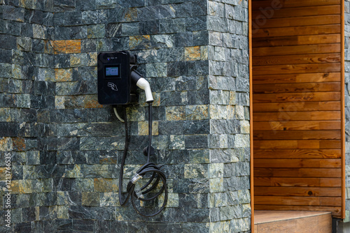 Obraz na płótnie Wall-mounted electric car charging station outside a modern house, representing sustainable transportation. Electrical cars industry. w salonie