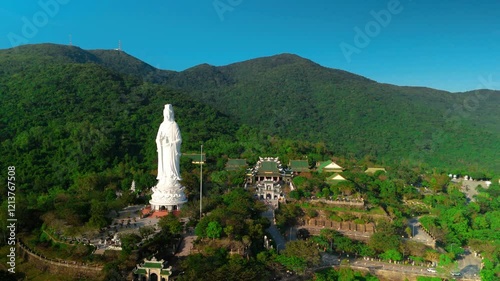 Aerial perspective revealing white lady buddha statue towering over verdant landscape near ho quoc pagoda, symbolizing spiritual tranquility on phu quoc island, vietnam