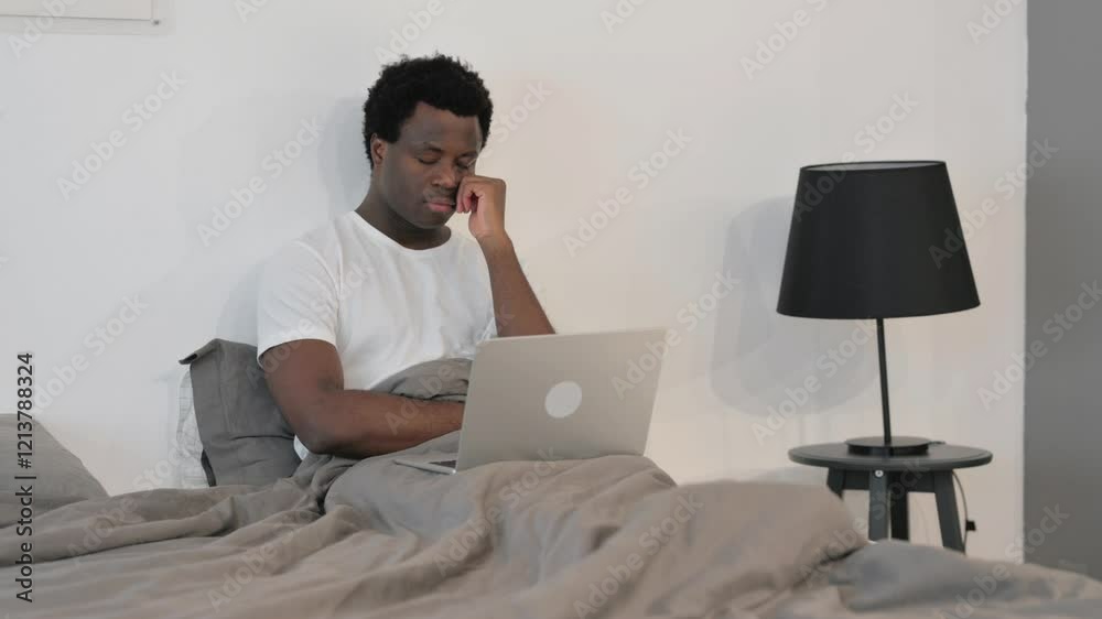 Tired African Man Sleeping while Working on Laptop while Sitting in Bed Tired African Man Sleeping while Working on Laptop while Sitting in Bed