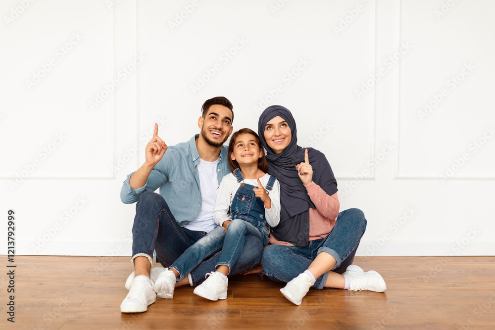 Portrait of smiling muslim people sitting on the floor leaning on white wall in new apartment, looking pointing fingers up. Cheerful man, woman and girl planning renovation design, showing copy space Portrait of smiling muslim people sitting on the floor leaning on white wall in new apartment, looking pointing fingers up. Cheerful man, woman and girl planning renovation design, showing copy space