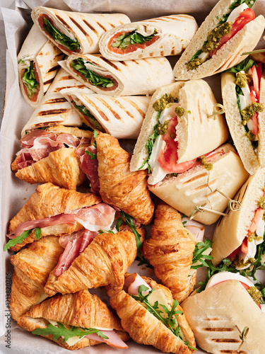 A vibrant display of assorted sandwiches and wraps, featuring croissants and tortillas filled with fresh ingredients, perfect for a casual gathering or lunch celebration