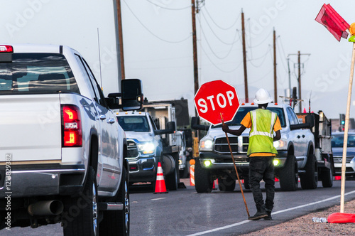 Foto A construction worker in a reflective vest and hard hat holds a stop sign to dir