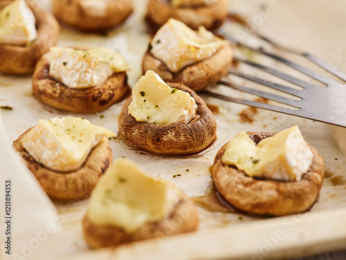 Savory mushroom caps are baked until tender and topped with creamy cheese. The dish is served warm on a rustic tray, ideal for a casual gathering or party