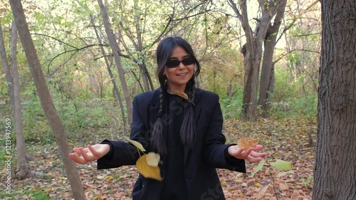 Woman enjoys a playful moment, throwing leaves and embracing the beauty of nature's seasonal transformation.
