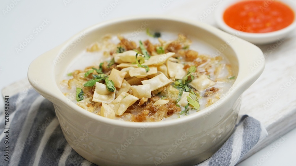 Close up Bubur Ayam, Indonesian rice porridge served with shredded chicken and wonton crackers isolated white background Close up Bubur Ayam, Indonesian rice porridge served with shredded chicken and wonton crackers isolated white background