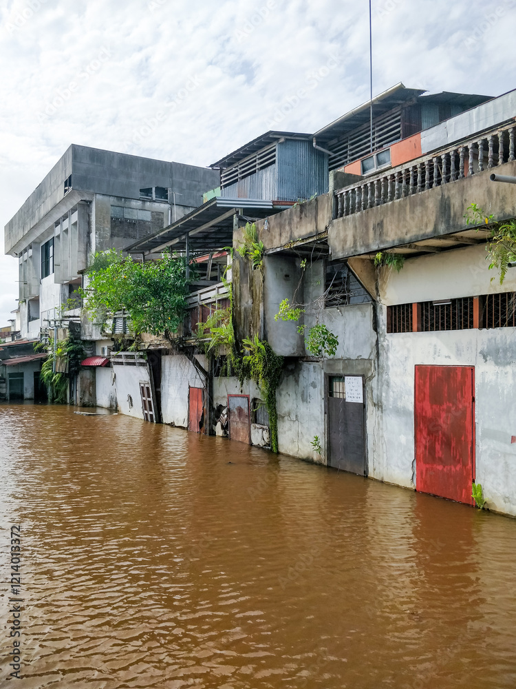Floodwaters rise around weathered riverside homes in Pontianak, Kalimantan Barat, highlighting the impact of tidal floods and climate crisis on local communities along the Kapuas River.