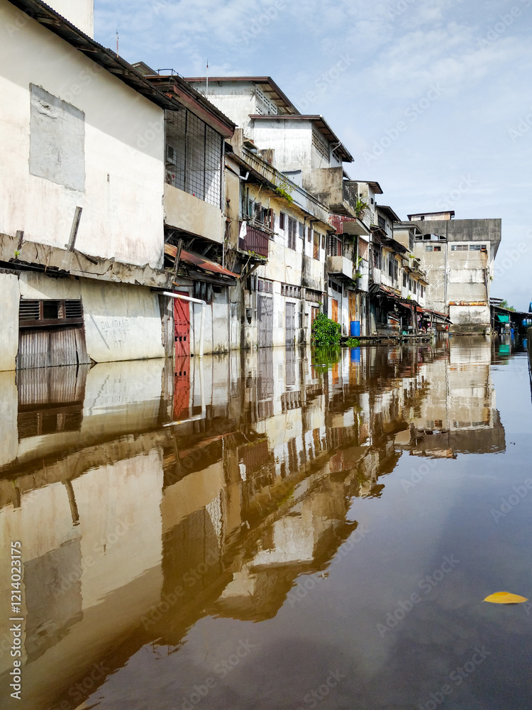 Floodwaters rise around weathered riverside homes in Pontianak, Kalimantan Barat, highlighting the impact of tidal floods and climate crisis on local communities along the Kapuas River.