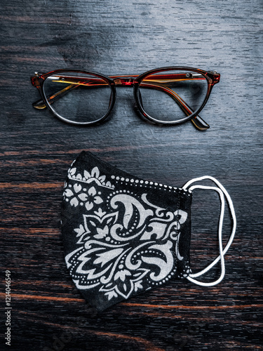 Obraz na płótnie Stylish glasses and a handmade floral mask placed on a dark wooden table, creating an appealing contrast. w salonie