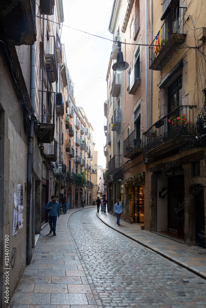Tourists walking down narrow cobblestone street in girona, spain