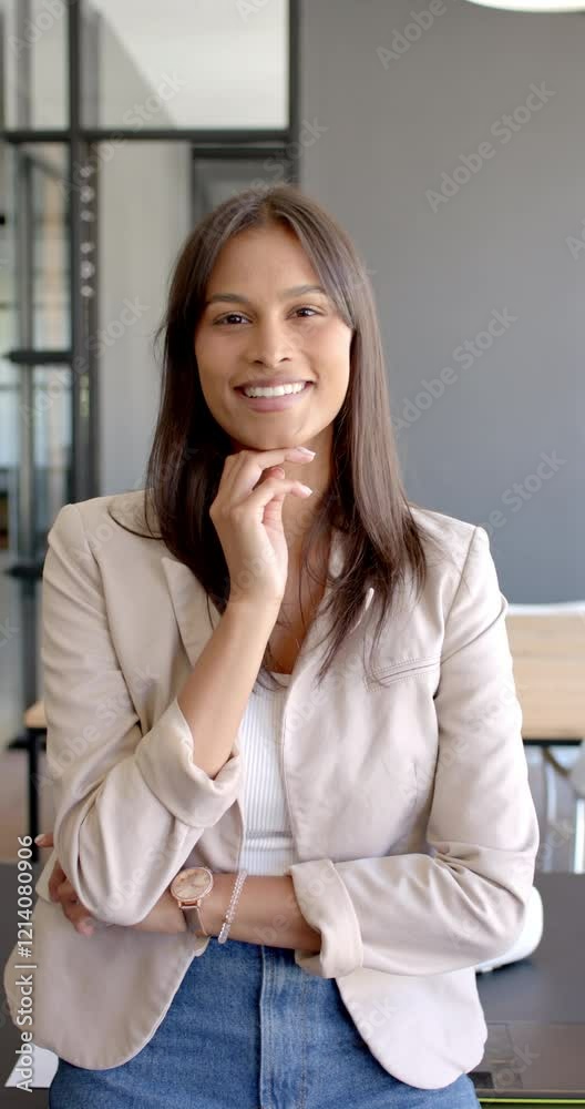 Vertical video: Smiling businesswoman standing confidently in modern office, wearing beige blazer