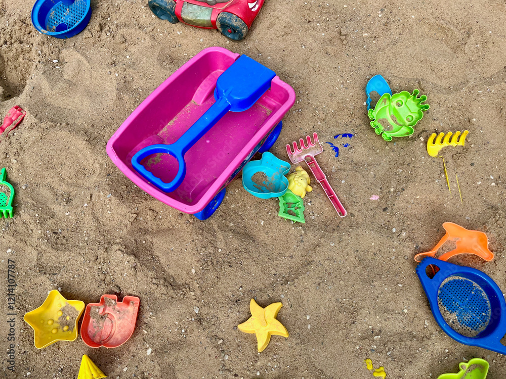 Toys are scattered in a large children's sandbox. Childhood and leisure of kid. Colorful plastic toy Toys are scattered in a large children's sandbox. Childhood and leisure of kid. Colorful plastic toy
