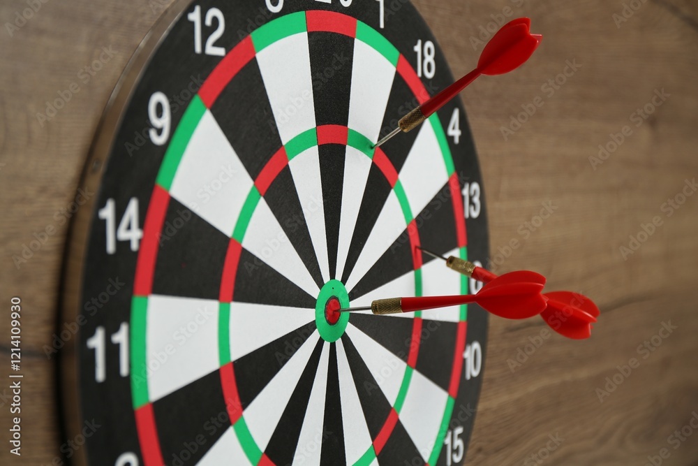 Dart board and red arrows on wooden background, closeup Dart board and red arrows on wooden background, closeup