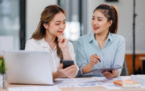 Asian Business women using calculator and laptop for doing math finance on an office desk  tax  report  accounting  statistics  and analytical research concept 