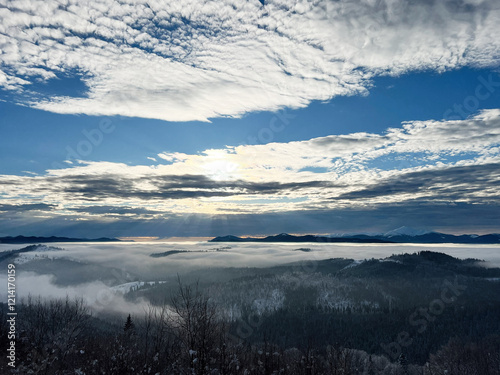 Scenic sunrise over mist-covered hills under a partly cloudy sky