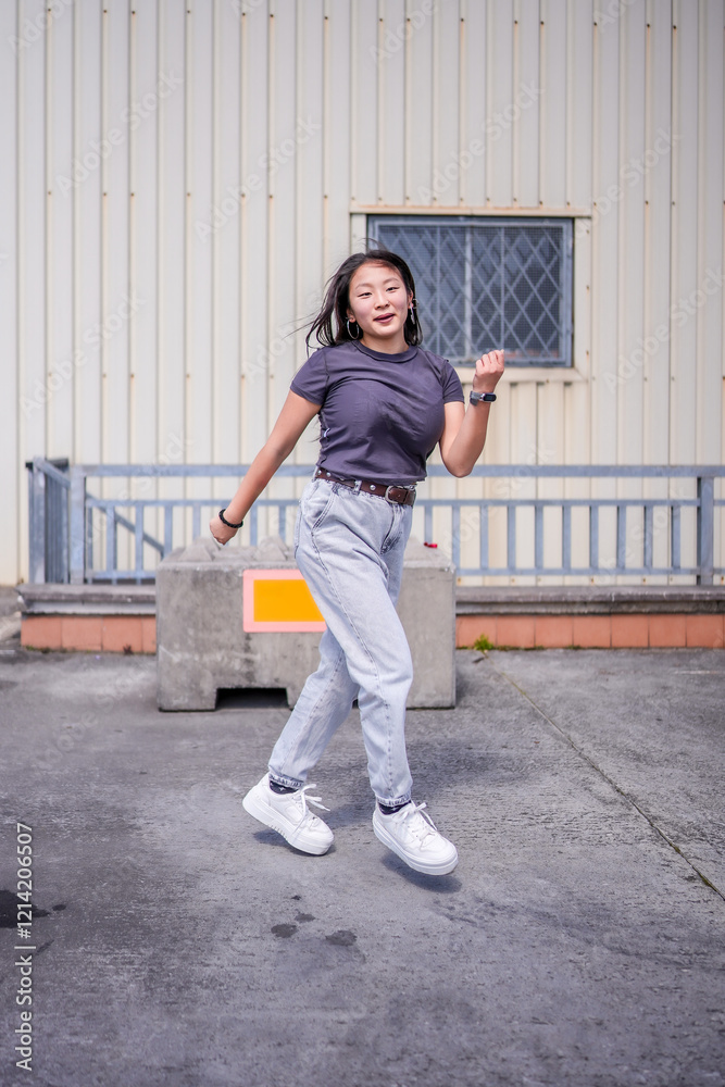 Asian student dancing k-pop next to an industrial building Asian student dancing k-pop next to an industrial building