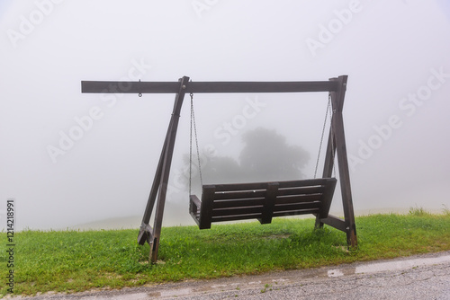 Obraz na płótnie a swing covered in fog on top of a mountain w salonie