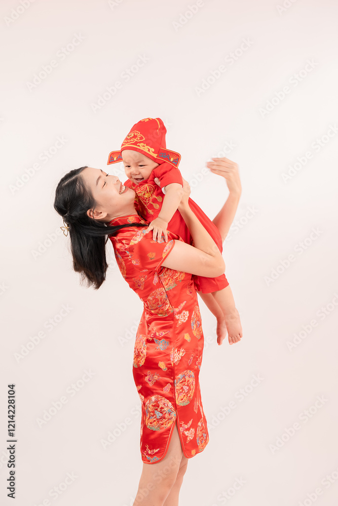 Obraz premium Chinese New Year theme, A young mother wearing Chinese traditional dress and her cute little children, in red costume with a smile on her face celebrating the Chinese festival together.