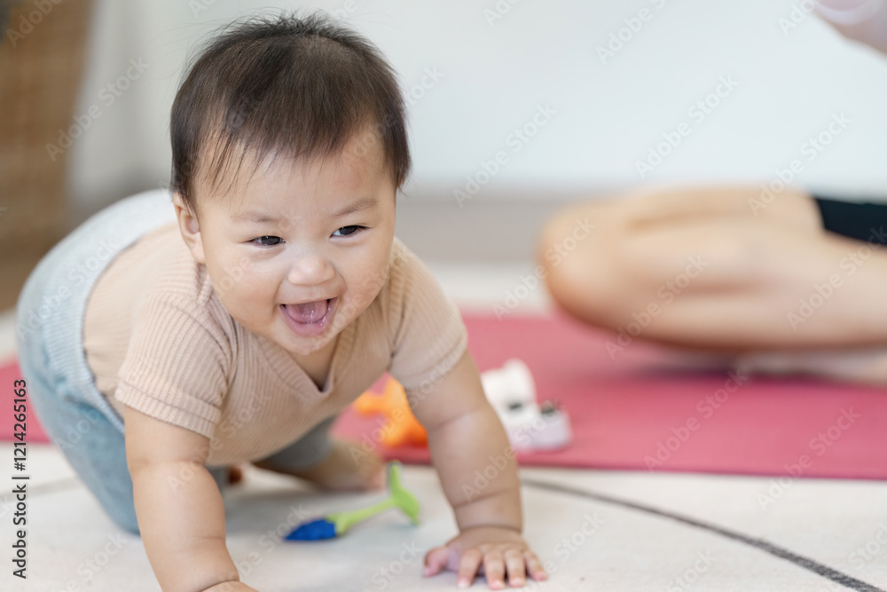 Joyful crawling baby exploring toys during playtime, with a multitasking mother nearby at home Joyful crawling baby exploring toys during playtime, with a multitasking mother nearby at home
