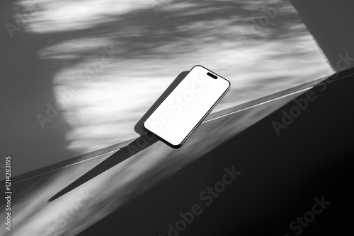 Blank smartphone mobile device on a white table mockup template in a room with shadows. Isolated blank surface to place your design. 