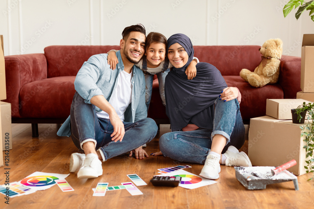Happy Loving Family. Portrait of smiling muslim people sitting on the floor with color palette, doing repair. Cheerful daughter embracing man and woman in hijab from behind, posing looking at camera Happy Loving Family. Portrait of smiling muslim people sitting on the floor with color palette, doing repair. Cheerful daughter embracing man and woman in hijab from behind, posing looking at camera
