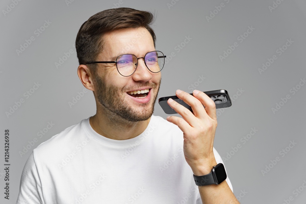 Man engages in a cheerful conversation using his smartphone in a gray backdrop during a bright day Man engages in a cheerful conversation using his smartphone in a gray backdrop during a bright day