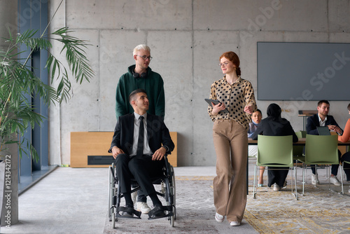 A diverse team of business colleagues, including a director in a wheelchair, engages in a collaborative discussion as they move together through a modern office space photo