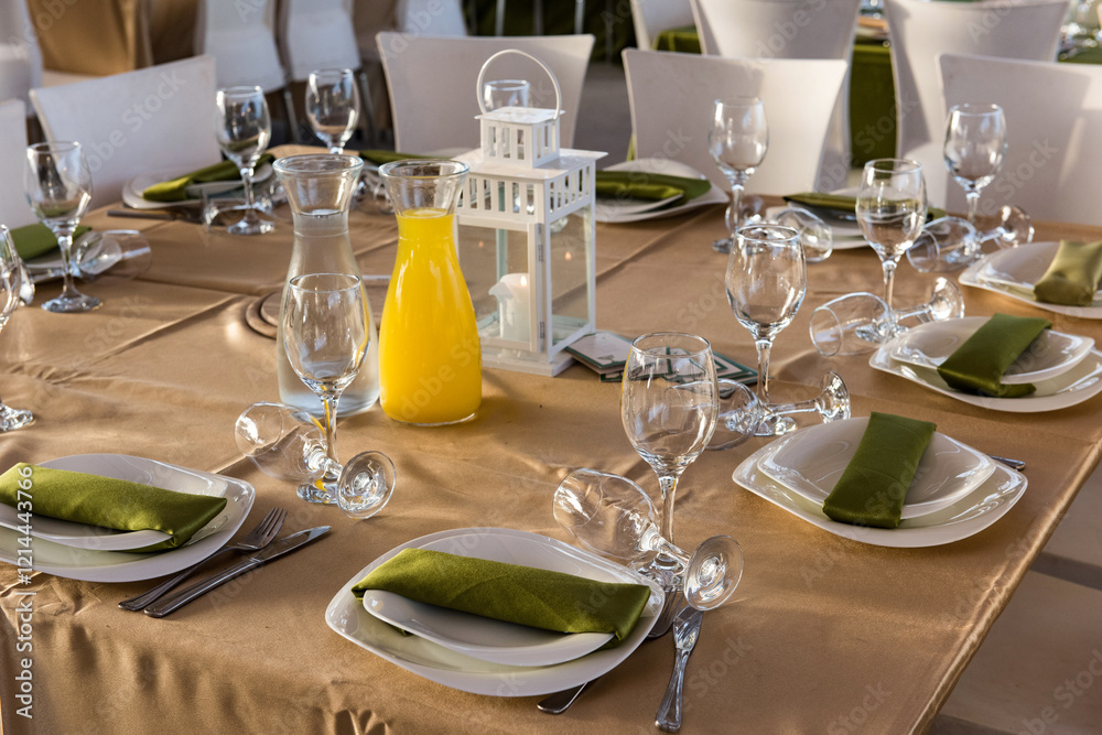 Fototapeta premium Elegantly set table with wine and water glasses, cutlery and napkins on a pressed cloth at a wedding banquet.