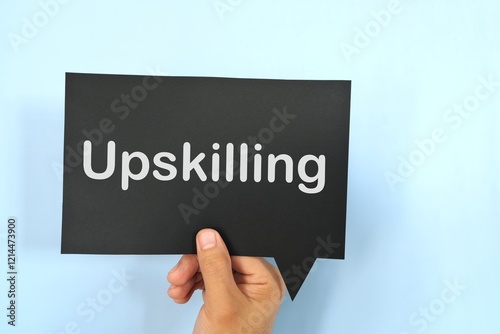 Human hand holding black speech bubble with written phrase Upskilling. Upskilling in workplace.